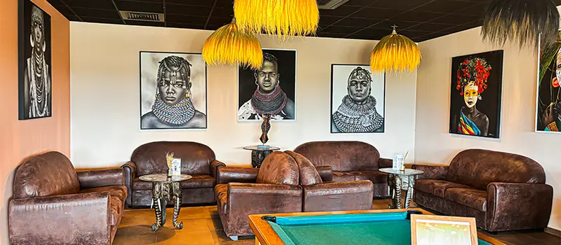 Espace lounge décoré avec canapés, billard et portraits muraux.