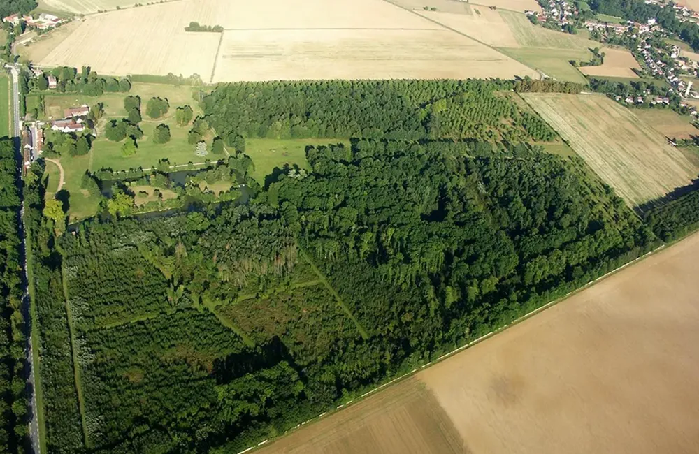 Vue aérienne du Lumigny Safari Reserve, avec de grands espaces boisés, des prairies et des champs environnants.